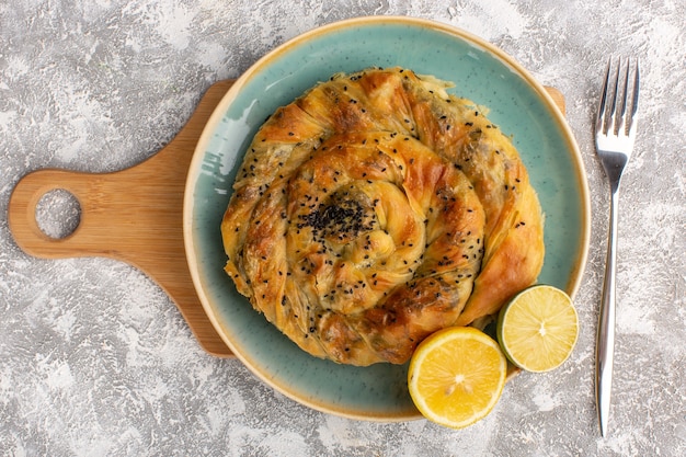 Top view of pastry with meat delicious dough meal inside plate with lemon slices on light surface