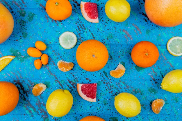 Top view of pattern of citrus fruits as orange lemon tangerine kumquat grapefruit on blue table