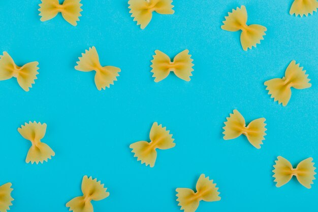 Top view of pattern of farfalle pasta on blue surface