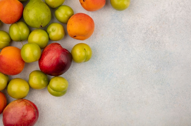 Top view of pattern of fruits as plum peach apricot and pear on white background with copy space