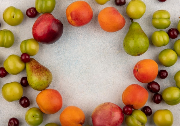 Вид сверху на узор из фруктов как сливовый персик и грушевую вишню на белом фоне с копией пространства