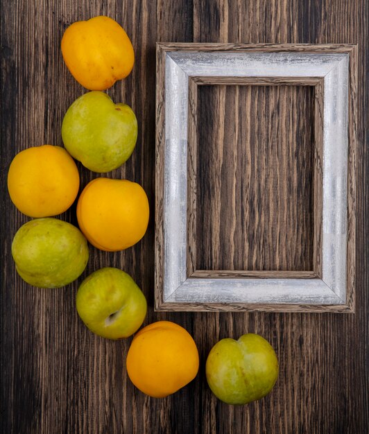 Top view of pattern of fruits as pluots and nectacots with frame on wooden background with copy space