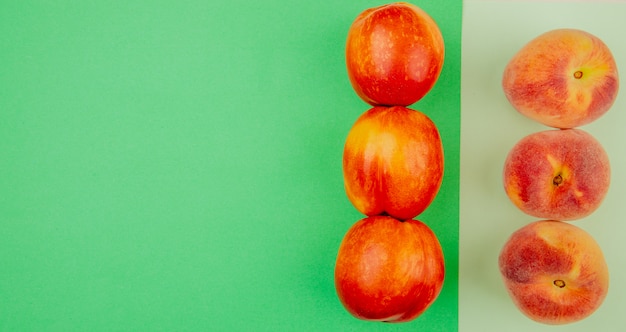 Free photo top view of pattern of peaches on right side and green and white surface with copy space