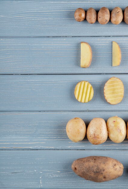 Top view of pattern of potatoes on right side and wooden background with copy space