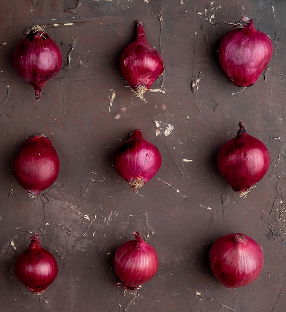 Free photo top view of pattern of red onions on maroon background with copy space