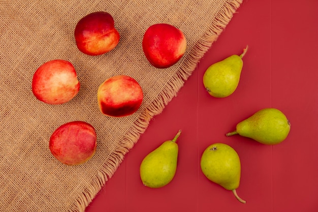 Free photo top view of peach isolated on a sack cloth and pears on a red background