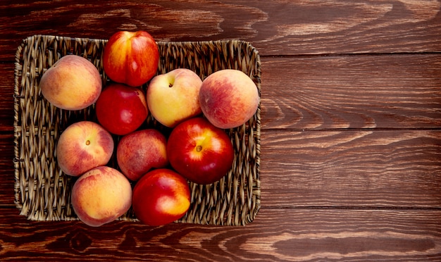 Top view of peaches in basket plate on left side and wood with copy space