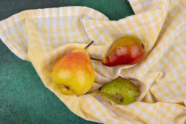 Top view of peaches on plaid cloth and green surface