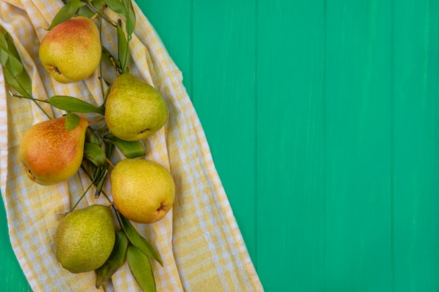Free photo top view of peaches on plaid cloth and green surface