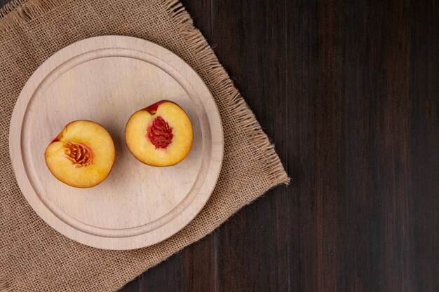 Top view of peaches with apricots and a green apple on a beige napkin on wooden surface