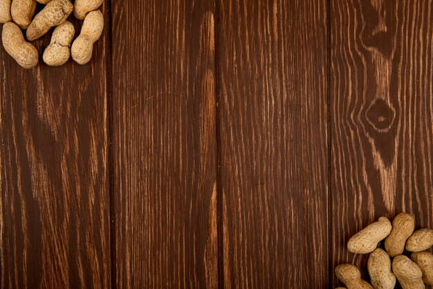 Top view of peanuts in shell scattered on wooden background with copy space