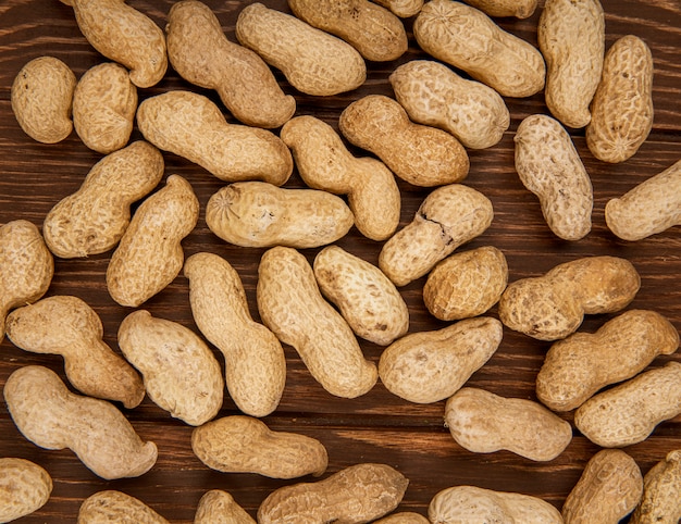 Top view of peanuts in shell scattered on wooden background