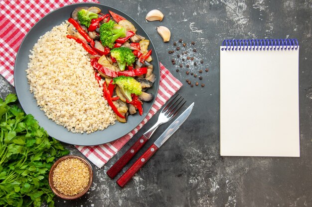 Top view pearl barley with tasty cooked vegetables and cutlery on grey table oil rice color meal photo healthy life diet