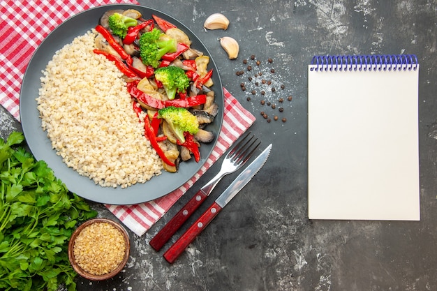 グレーのテーブルオイルライスカラーミール写真健康的な生活の食事療法のおいしい調理された野菜とカトラリーとトップビューパール大麦
