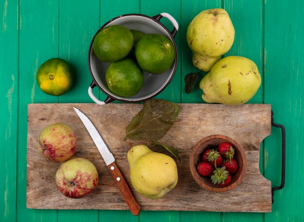 Top view pears with apples tangerines and strawberries on a cutting board