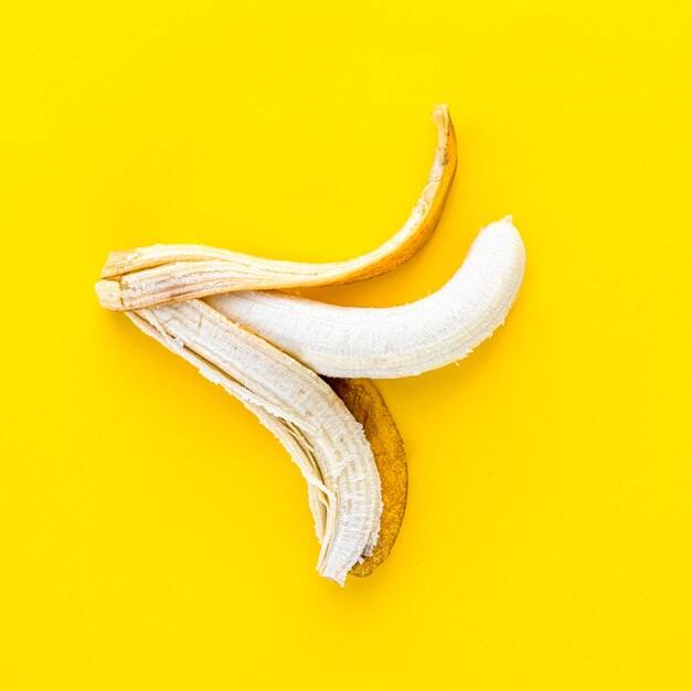 Top view peeled banana on yellow background