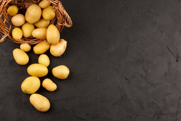 Top view peeled out potatoes whole inside basket on the dark floor