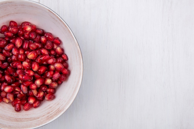 Top view of peeled pomegranate in a bowl on a white surface