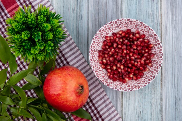 Top view of peeled pomegranate on a plate on a red checkered towel on a gray surface