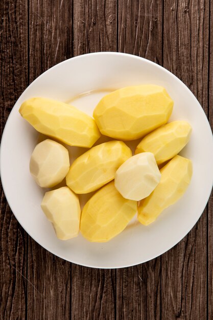 Top view peeled potatoes on wooden background