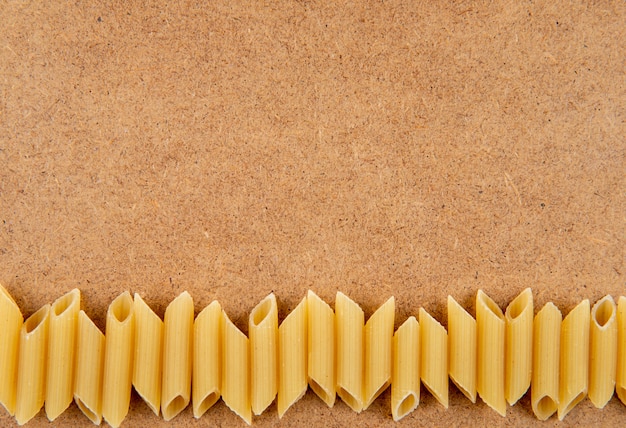 Pasta del penne di vista superiore sul fondo con lo spazio della copia su fondo marrone