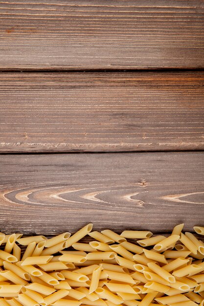 Top view penne pasta on the bottom with copy space on wooden background