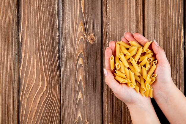 Top view penne pasta on the right with copy space on wooden background