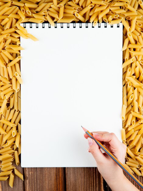 Top view penne pasta with copy space on wooden background