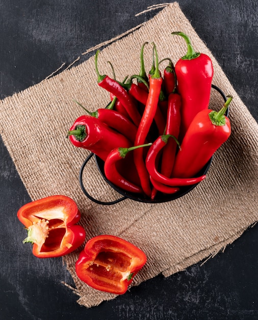 Foto gratuita peperone dolce e peperoncino rosso del peperone di vista superiore in pentola nera sul panno di tela sul verticale di pietra nero