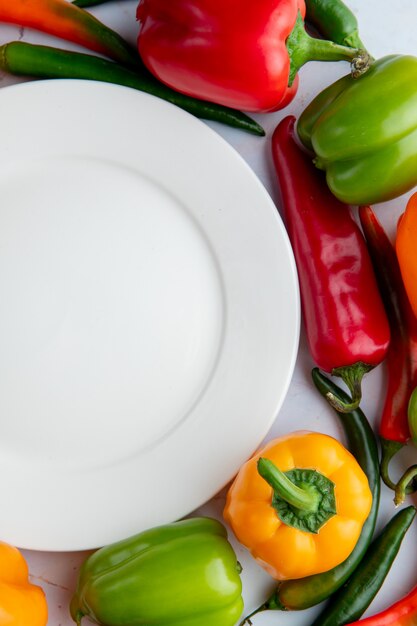 Top view of peppers and plate on white background