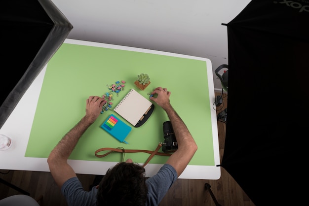 Top view of a person arranging stationery over table near camera and succulent plant in studio