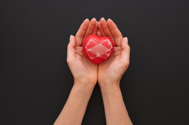 Top view of person holding broken heart put back together with scotch tape