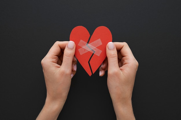 Top view of person holding broken heart put back together with scotch tape