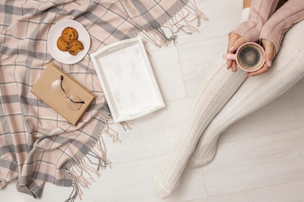 Top view of person holding coffee mug with cookies and tray