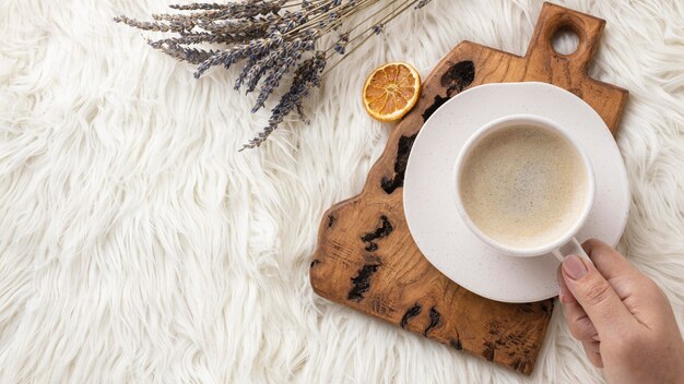 Top view of person holding cup of coffee with lavender and dried citrus