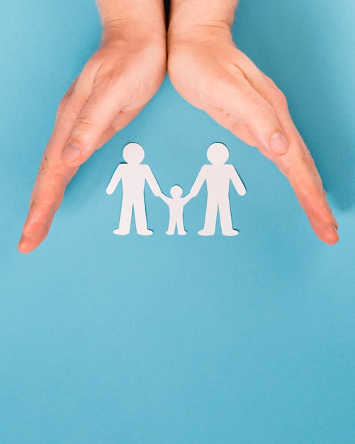 Top view person holding in hands cute paper family with copy space