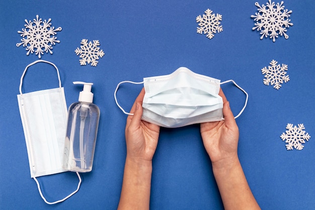 Free photo top view person holding medical mask near snowflakes