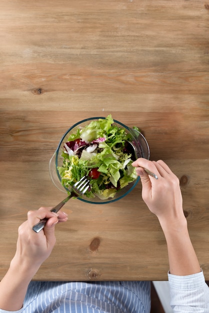 Top view of person preparing healthy salad in bowl