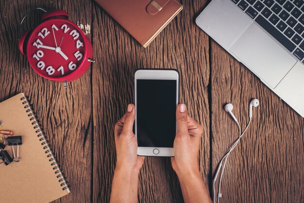 Top view phone and workspace on wood background