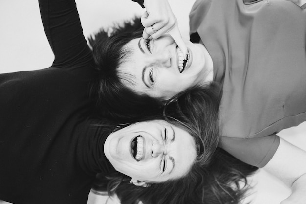 Free photo top view photo of happy girl friends relaxing head to head while happy smiling. friendship concept