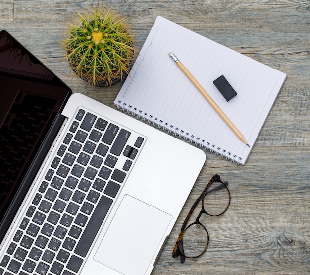 Top view photo of laptop computer and paper notebook on wooden background and copyspace. business working space concept.