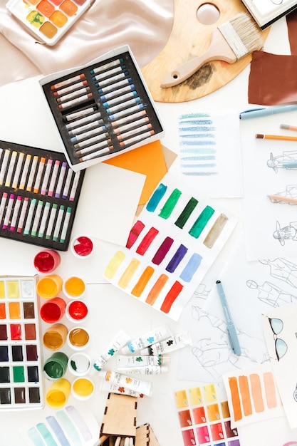 Top view photo of a lot of fashion illustrations and crayons on the table