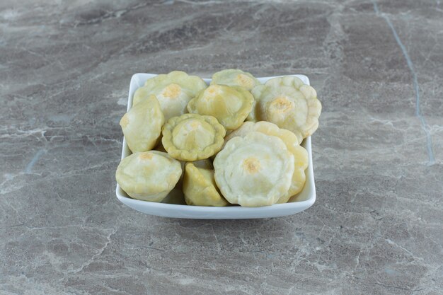 Top view of pickle Green patty pan squash in white bowl