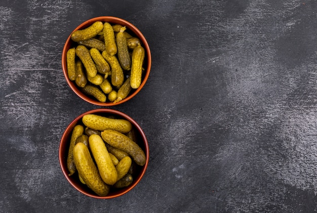 Top view pickled cucumber in bowls with copy space on right on black stone  horizontal