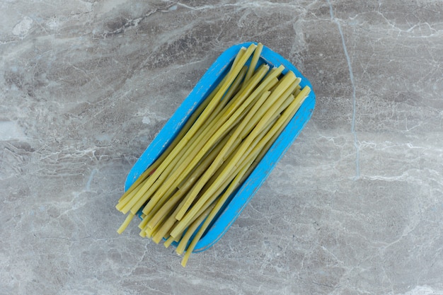 Free photo top view of pickled green stick on blue wooden board.