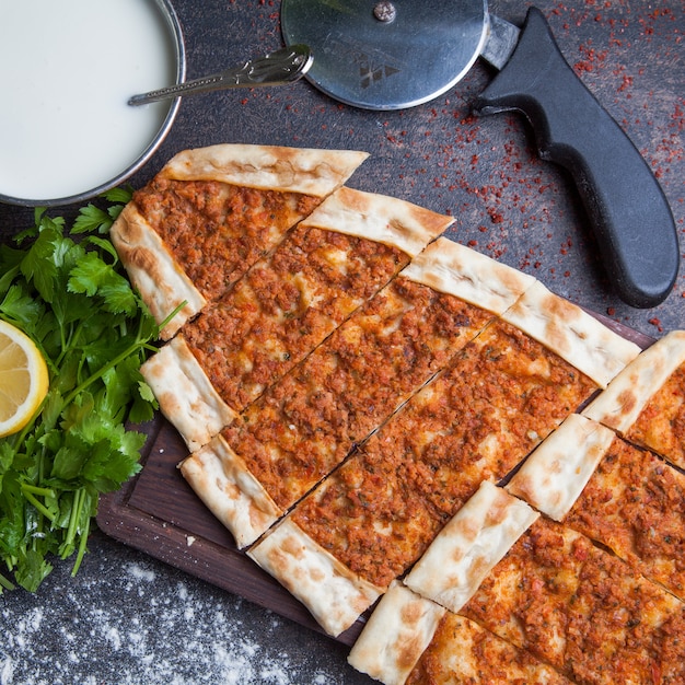 Free photo top view pide with minced meat and ayran and pizza knife in cutting board