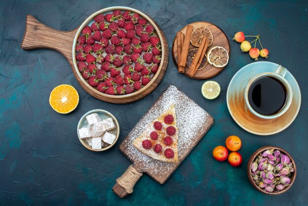 Top view piece of cake baked sweet with raspberries and tea on dark floor berry sugar cake pie bake biscuit