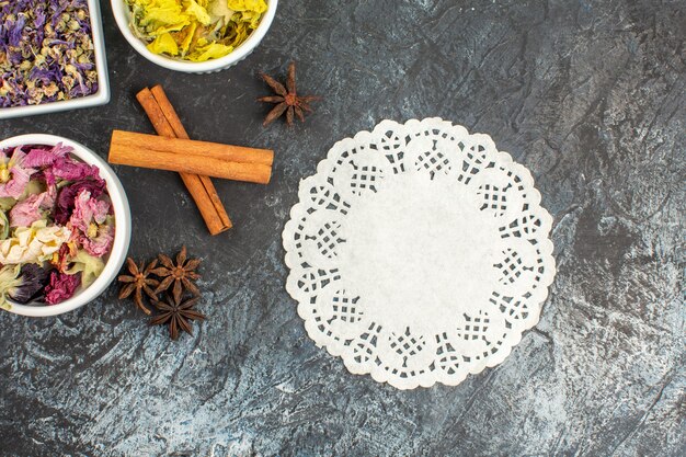 Top view of a piece of lace and dry flowers and cinnamon on grey ground