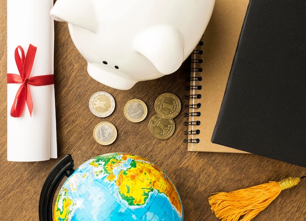 Top view of piggy bank with notebooks and diploma