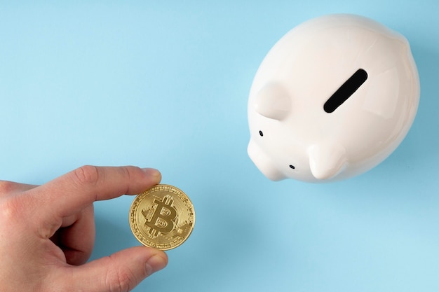 Top view piggy bank with person holding a bitcoin
